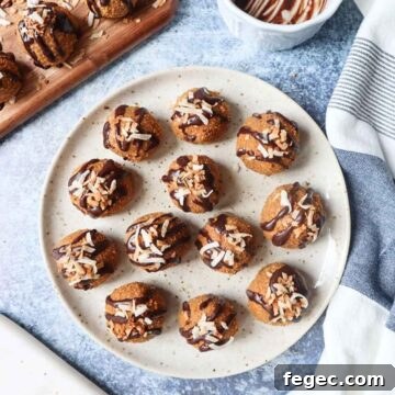 white plate with various biscoff balls topped rolled in crushed biscoff cookies and topped with chocolate drizzle and toasted coconut with chocolate bowl and toasted coconut on a cutting board
