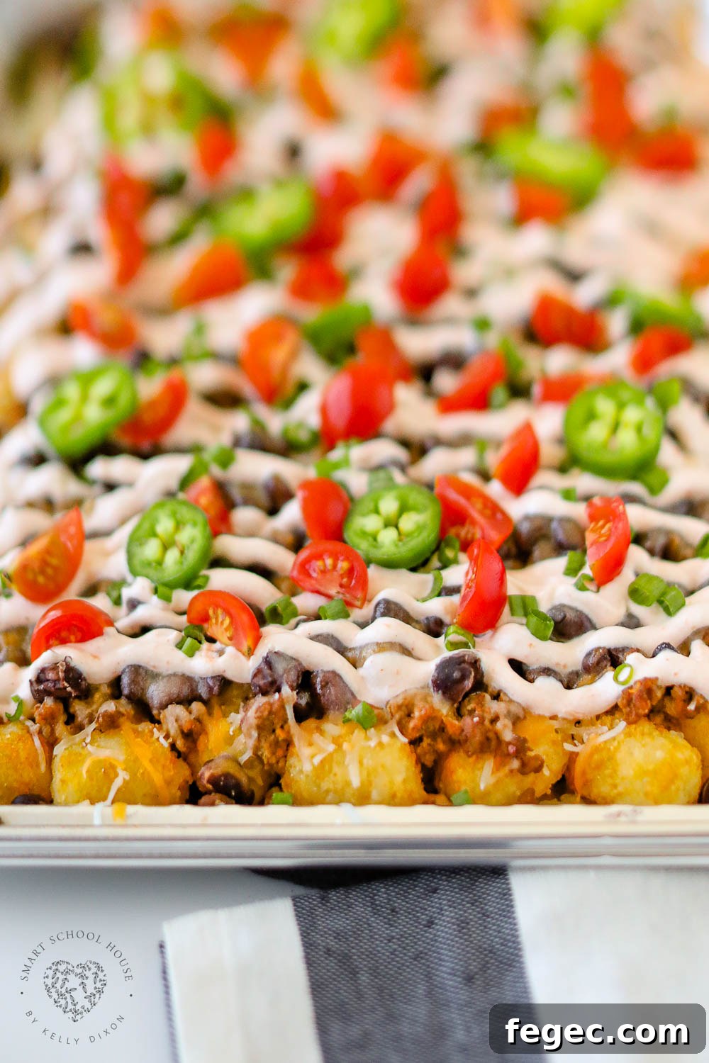 Creamy cheesy Tatchos recipe! Tater tot nachos are layered meat, cheese, and a delicious creamy drizzle!