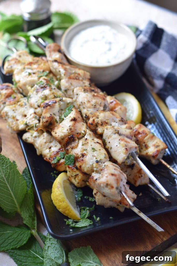 Chicken kebabs on a plate with a dip.