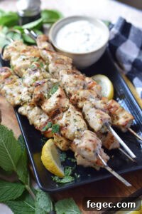 Chicken kebabs on a plate with a dip.