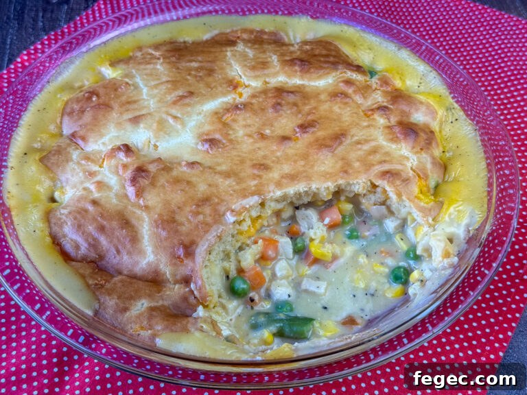 Overhead view of a beautiful and easy chicken pot pie with bisquick baking mix with the creamy chicken and veggie mixture filling a corner of the pie plate where a scoop was taken out.