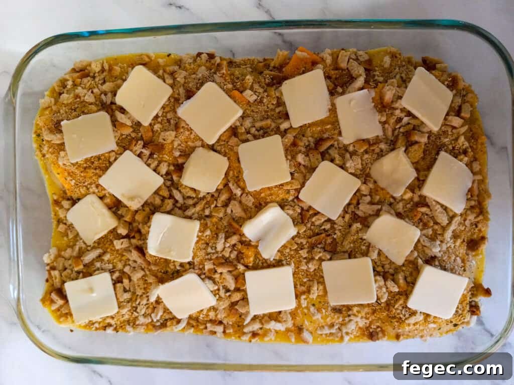 butter slices on top of the stuffing and chicken dish, ready to bake.