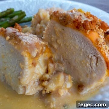 Amish oven-baked creamy chicken breast cut in half on a plate with rice and asparagus